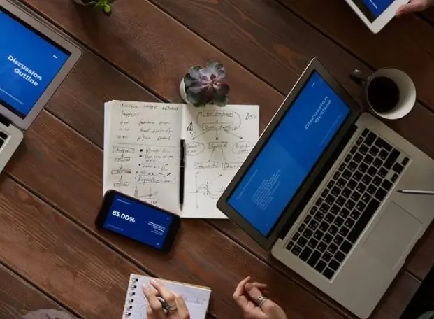 A notebook of working, open beside a laptop.